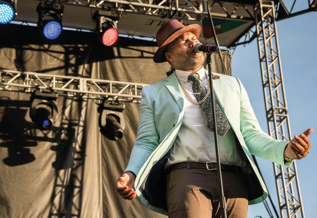 Artist in a wide-brim hat performing live